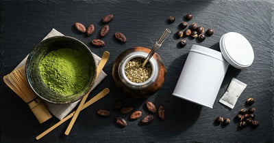Caffeine without coffee — matcha bowl, yerba mate gourd, and focus pouch tin arranged on dark slate with cacao beans and guarana seeds