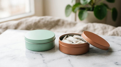 Two nootropic pouch tins side by side β one open showing white pouches inside, on white marble surface